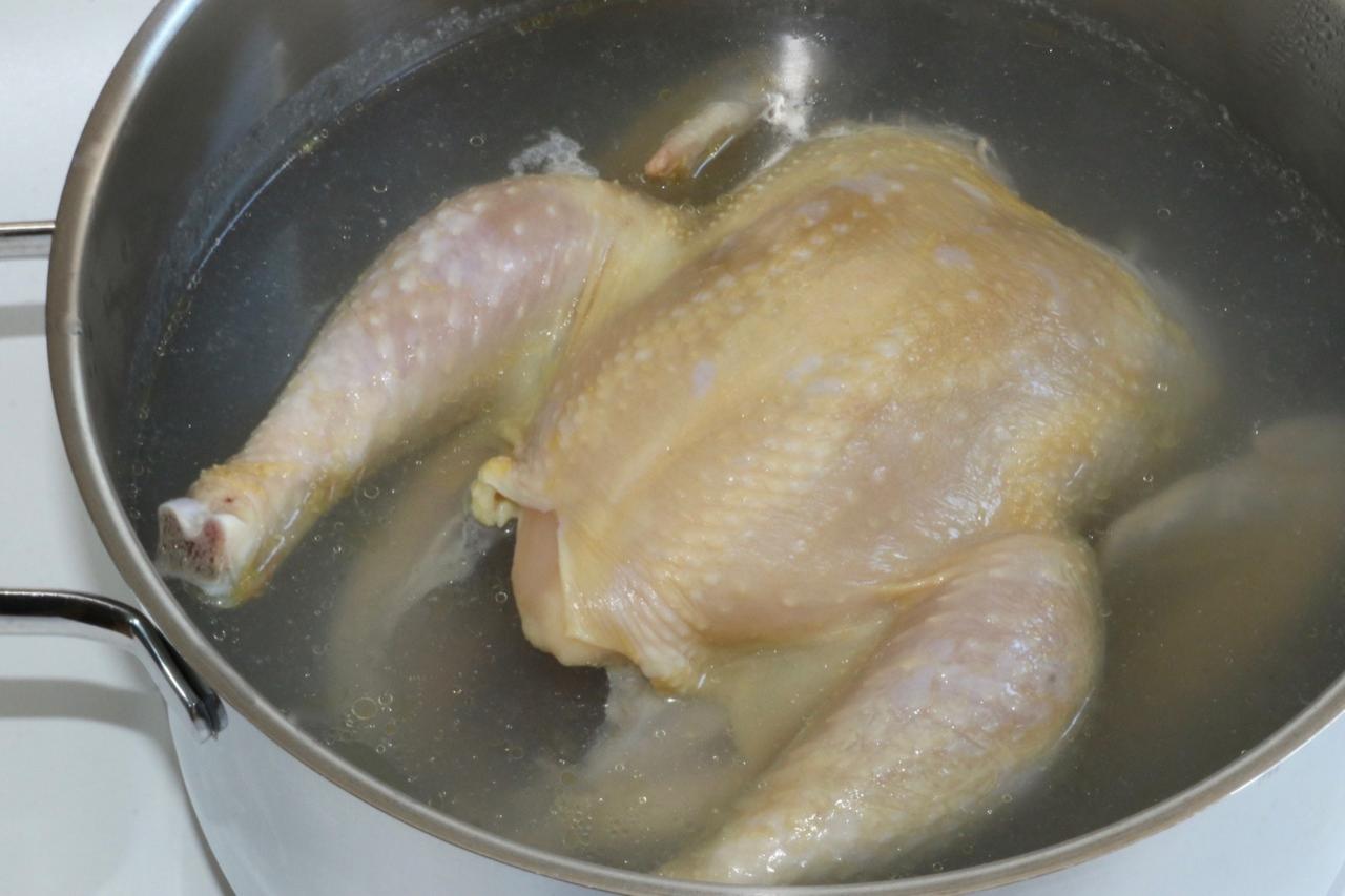 2 Liter Wasser in einem mittleren Topf aufkochen, Huhn hineinlegen, zudecken und schon mal köcheln lassen.